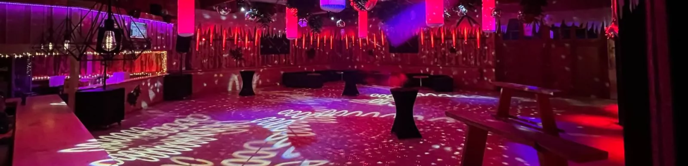 Altes Sägewerk Großzügiger Veranstaltungsraum mit bunten Lichtern und dekorativem Bodenmuster.