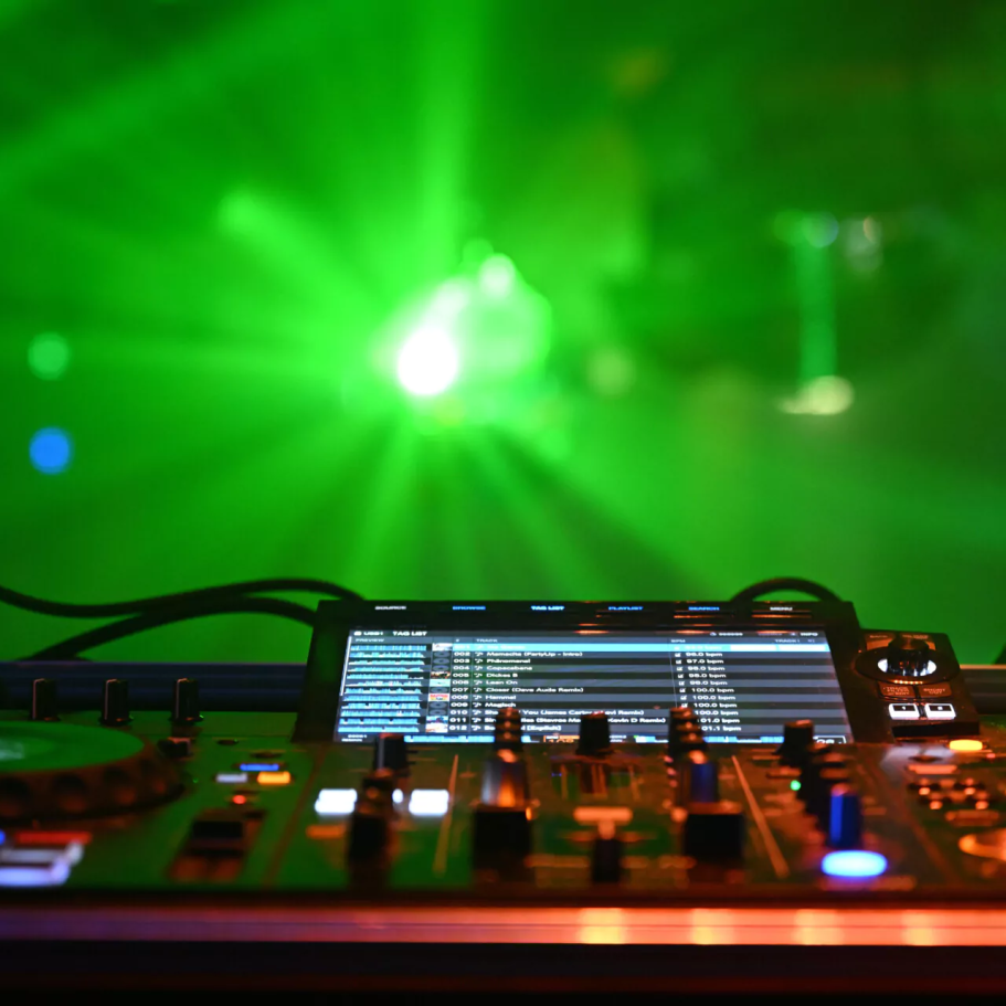 Events DJ-Pult mit Lichtern und Nebel, grüne Strahlen beleuchten die Umgebung.