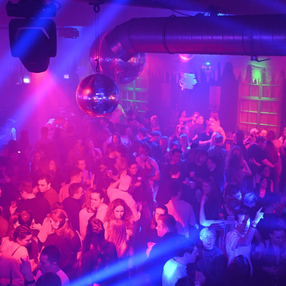 Altes Sägewerk Bunte Lichtshow in einem vollen Club mit Menschen, die tanzen und feiern.